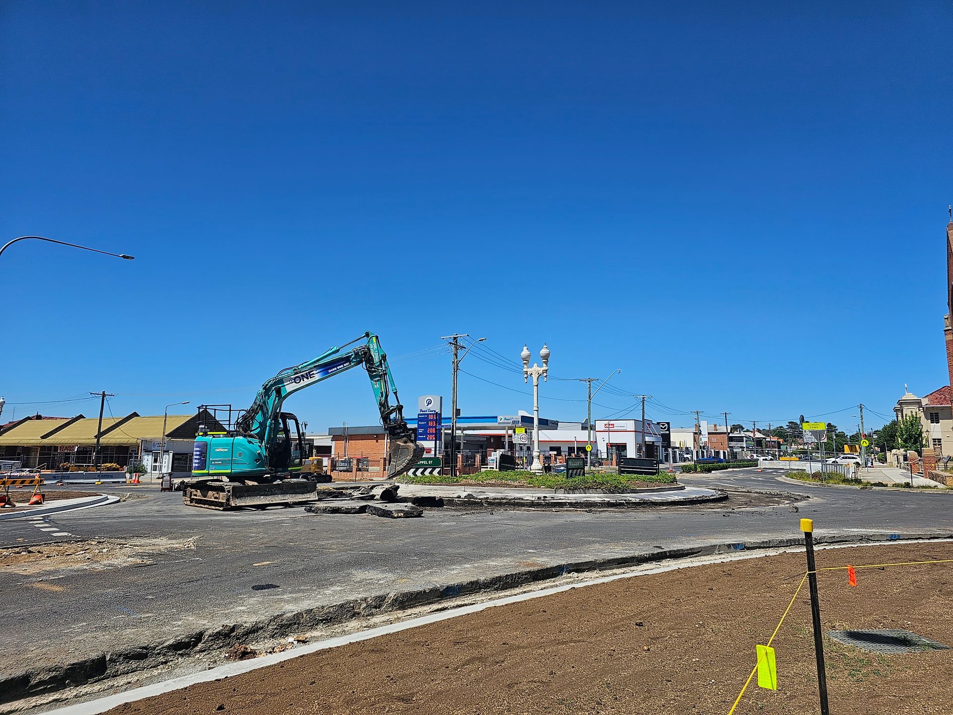 An excavator working on a roundabout under a clear blue sky — One Group Industries Pty Ltd in Bathurst, NSW