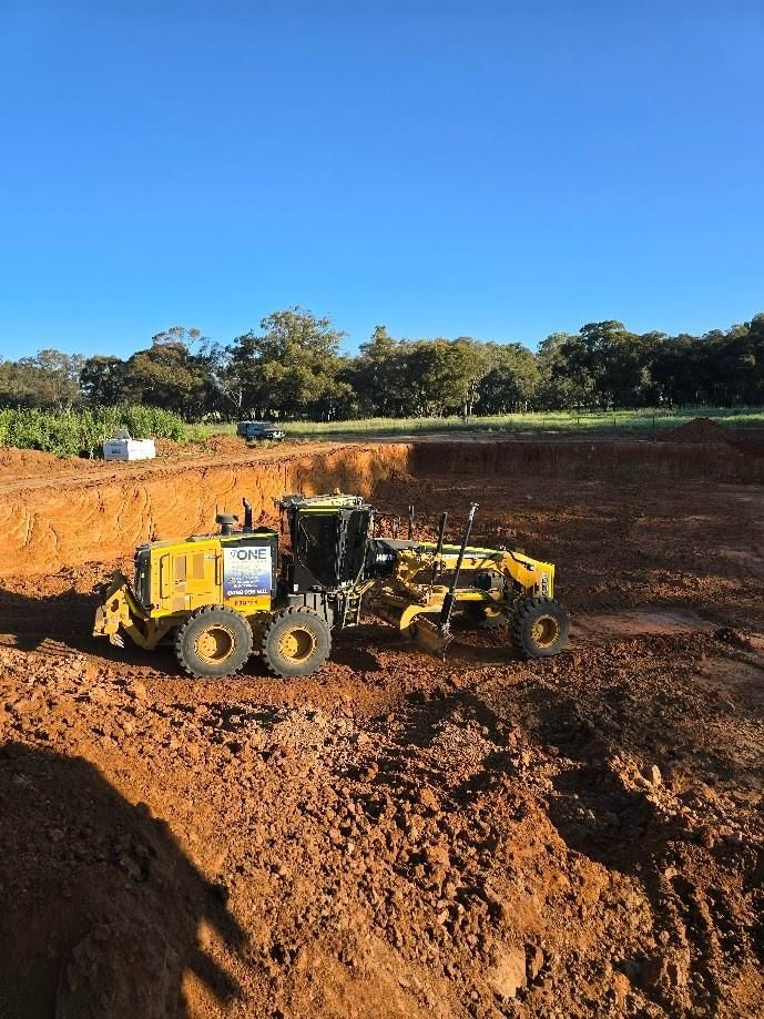 A Grader Levels Dirt in A Construction Site — One Group Industries Pty Ltd in Bathurst, NSW