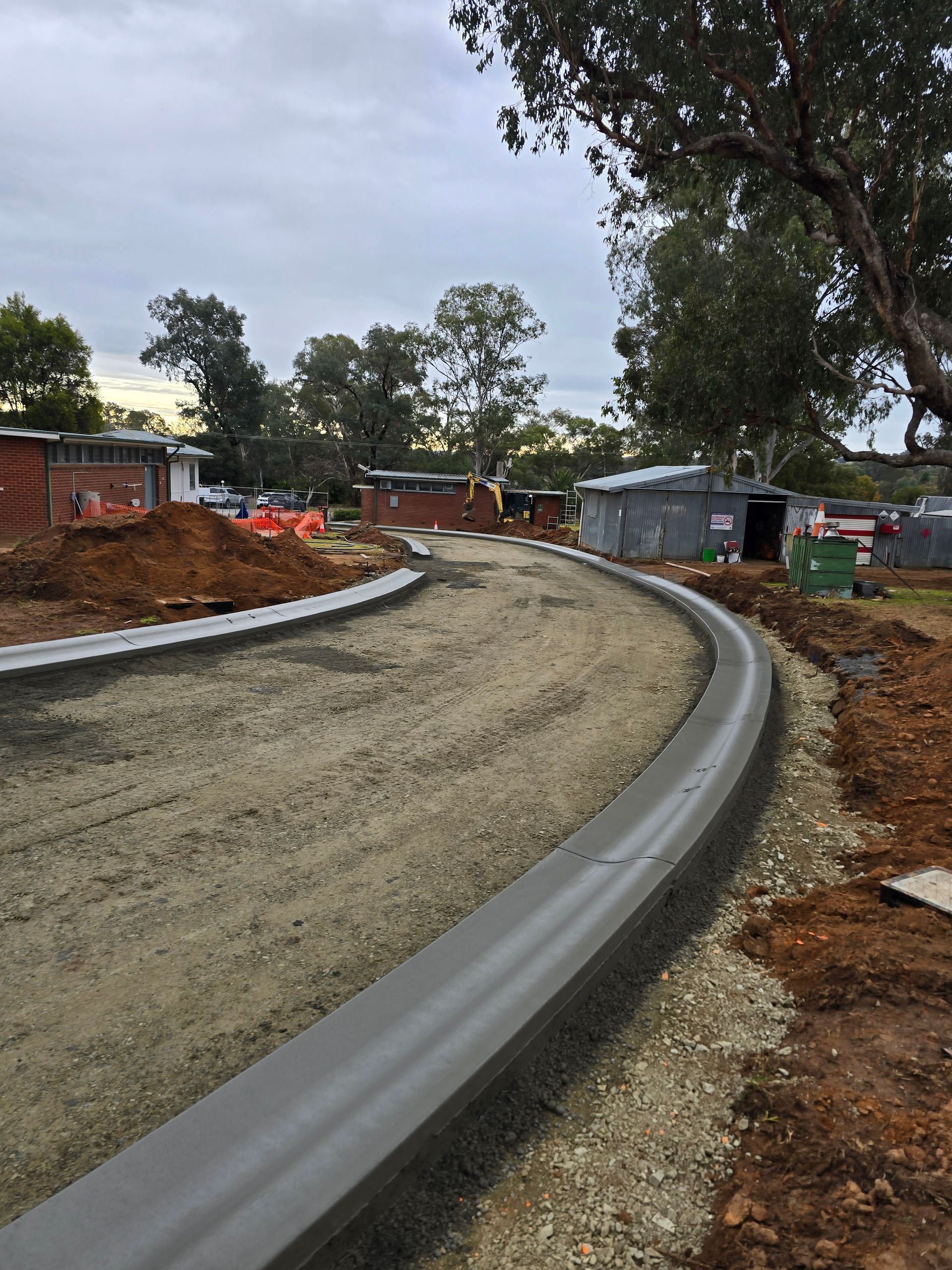 Newly constructed concrete curb along a gravel road — One Group Industries Pty Ltd in Bathurst, NSW