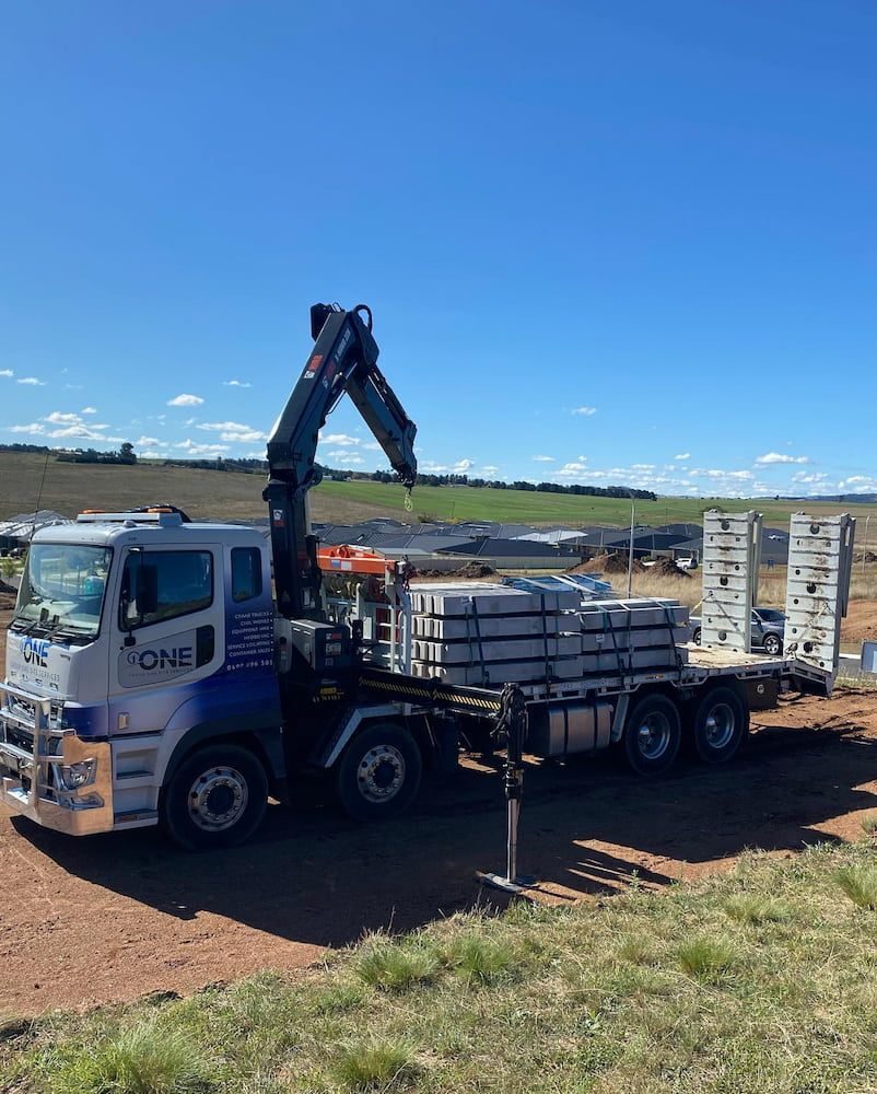 A Truck With a Crane on the Back is Parked in a Dirt Field — One Group Industries Pty Ltd in Bathurst, NSW
