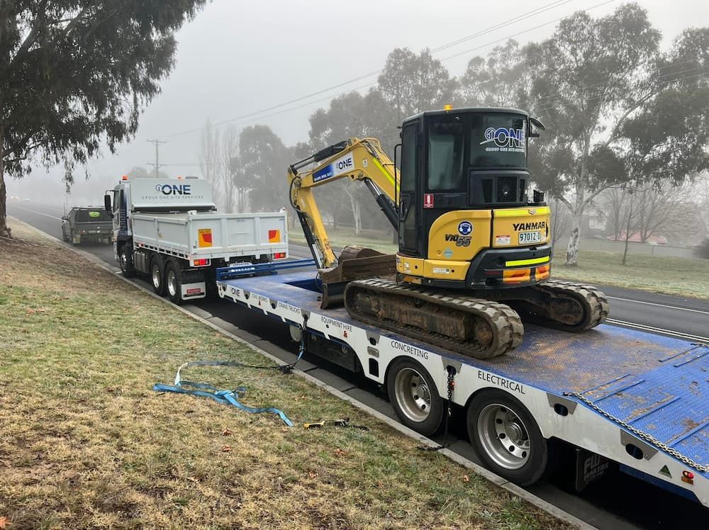 A Yellow Excavator is Sitting on Top of a Flatbed Trailer — One Group Industries Pty Ltd in Bathurst, NSW
