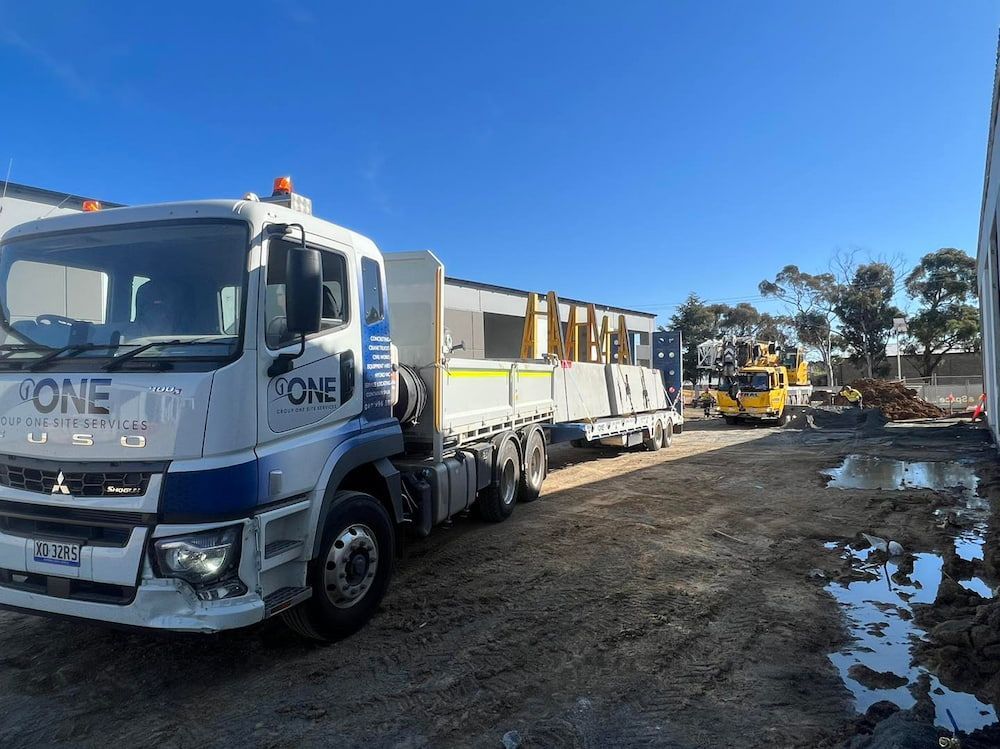 A White Truck is Parked in a Dirt Lot Next to a Building — One Group Industries Pty Ltd in Bathurst, NSW
