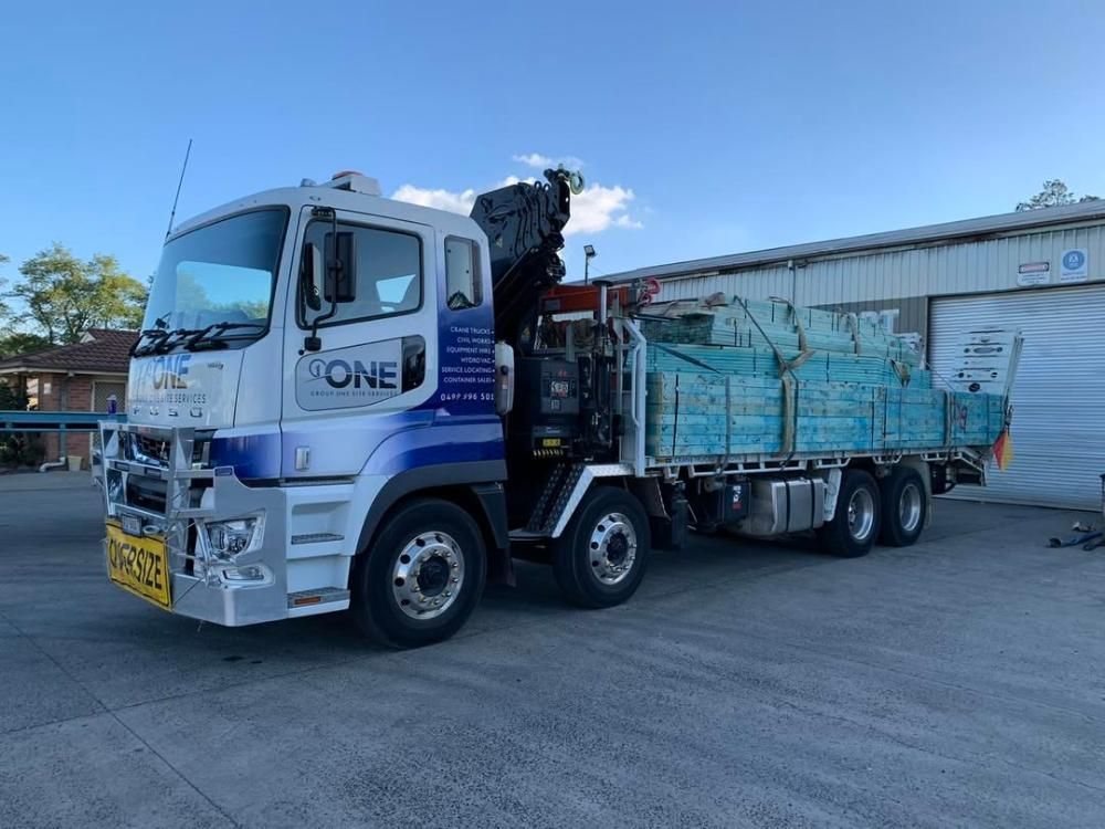 A Truck With a Crane on the Back is Parked in Front of a Building — One Group Industries Pty Ltd in Bathurst, NSW