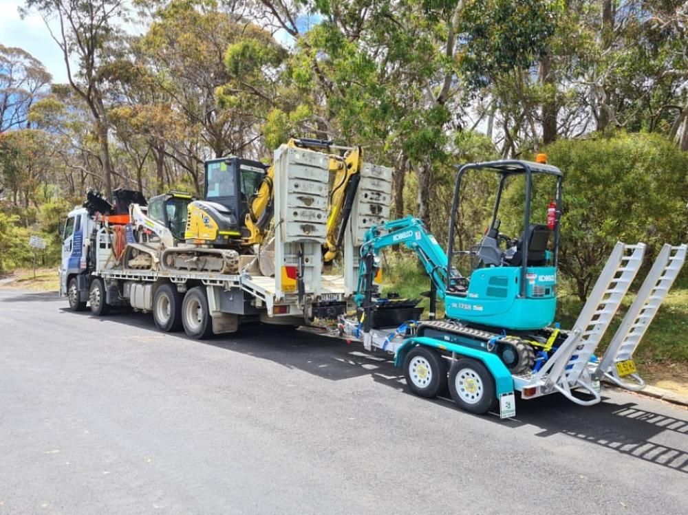 A Truck is Carrying a Small Excavator on a Trailer — One Group Industries Pty Ltd in Bathurst, NSW