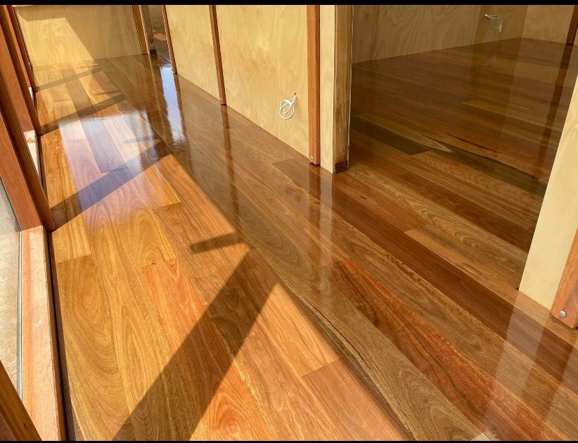 Sunlit hardwood hallway with glass railings and warm wood walls — Finer Floors In Cambridge, TAS