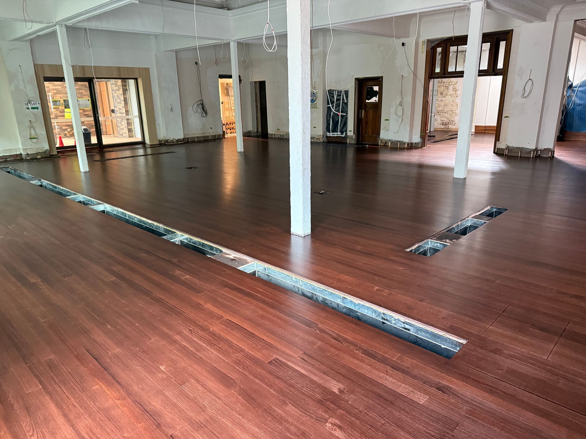 Empty room with white columns and dark wood flooring, shown during renovation or installation — Finer Floors In Cambridge, TAS