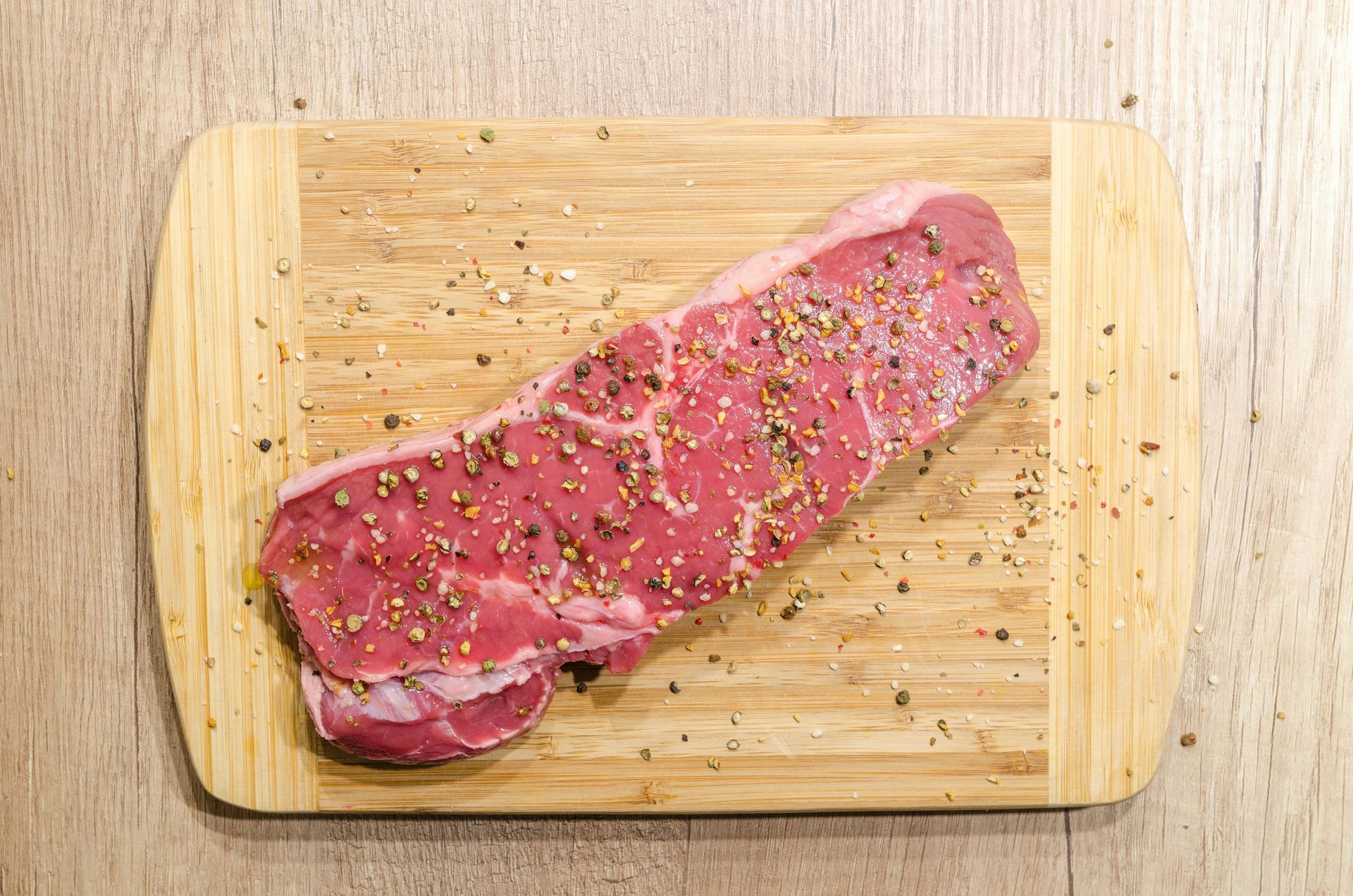 Raw chicken breasts with rosemary, garlic, and bay leaves on a dark slate surface.