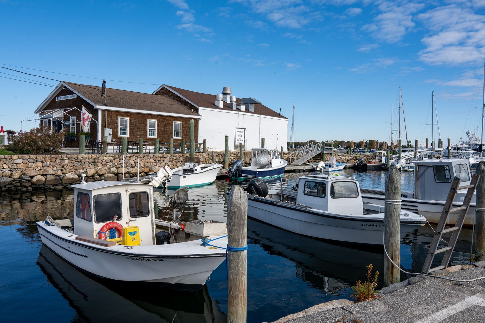 Harbor with small fishing boats moored beside waterfront buildings on a sunny day
