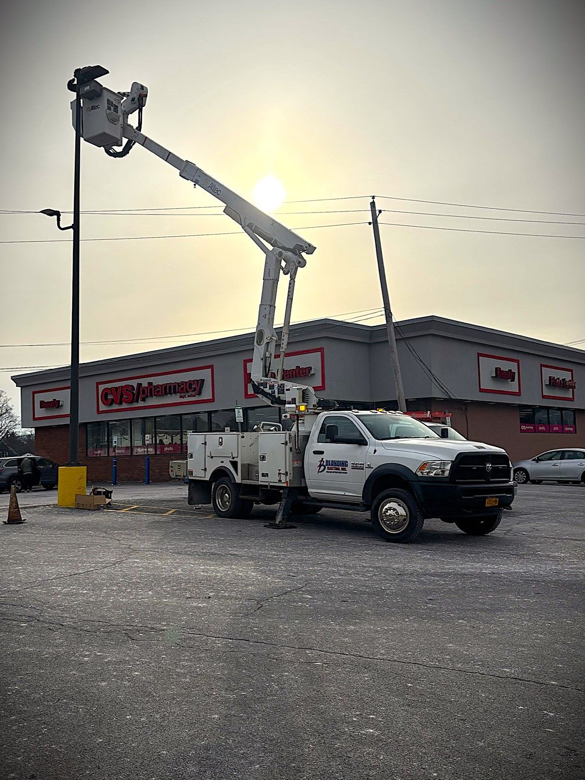 Bucket truck working outside a storefront at sunset