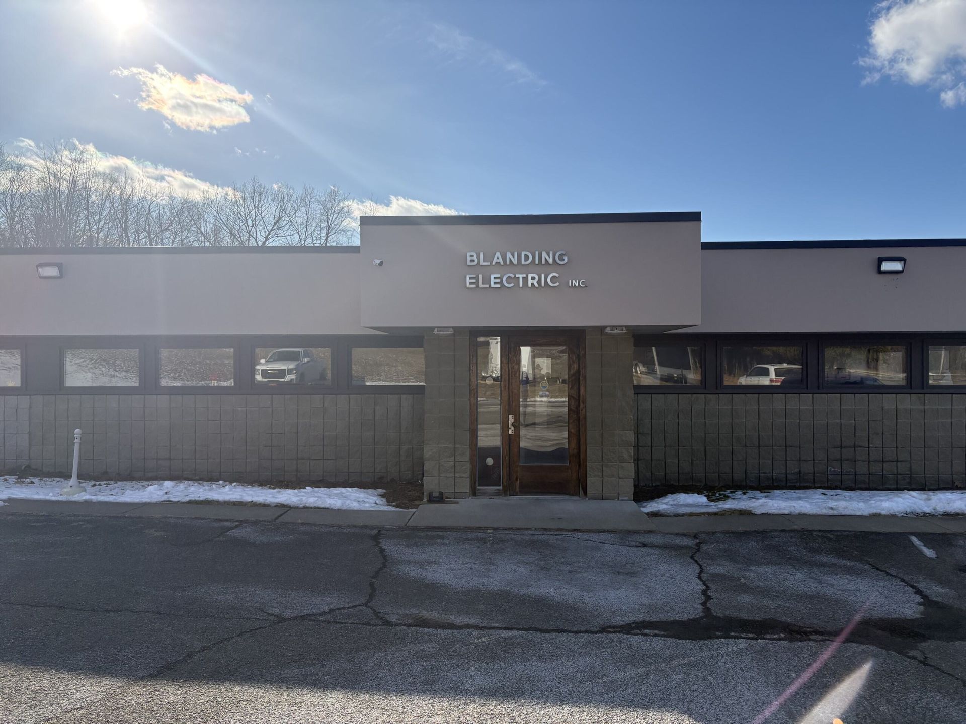 Snowy front view of a small medical clinic with a glass entrance under a bright blue sky.