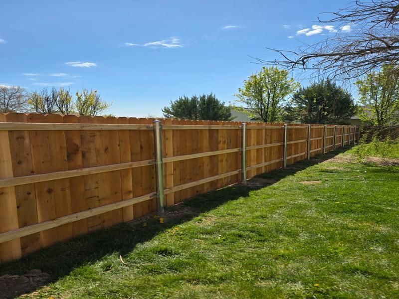 Wooden privacy fence along a grassy yard under a blue sky
