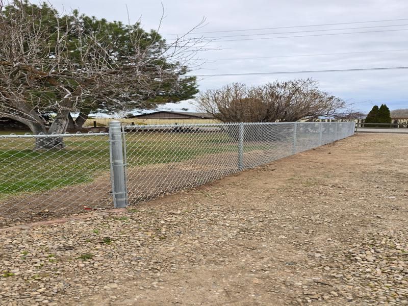 Chain-link fence along a grassy field under cloudy skies