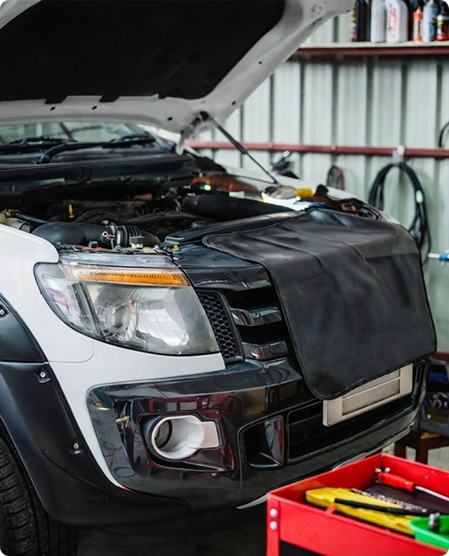 Black SUV in a garage with hood open, front covered by a black protective mat for maintenance | Joe's Garage