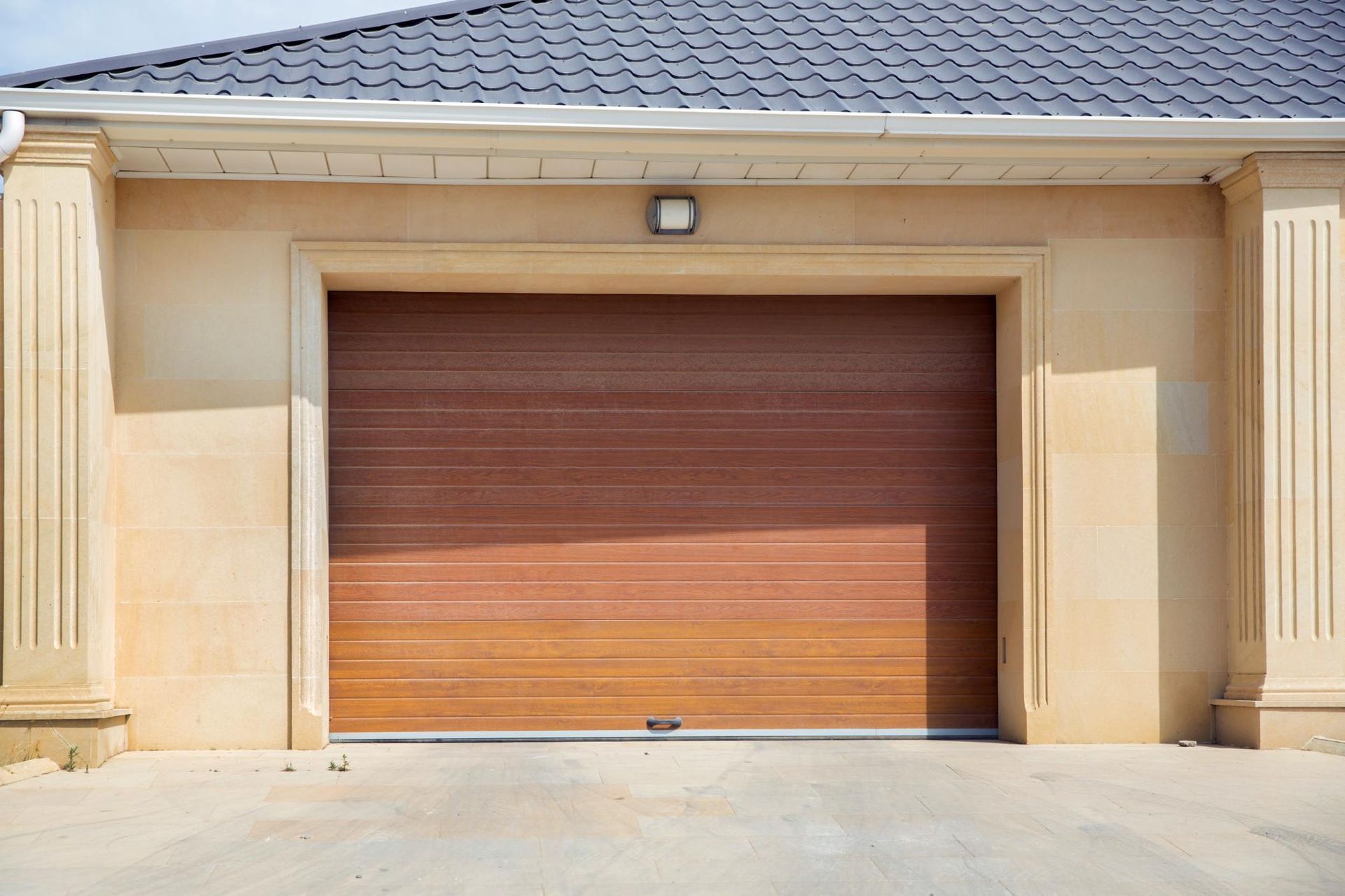 Closed wooden garage door on a beige house exterior in daylight