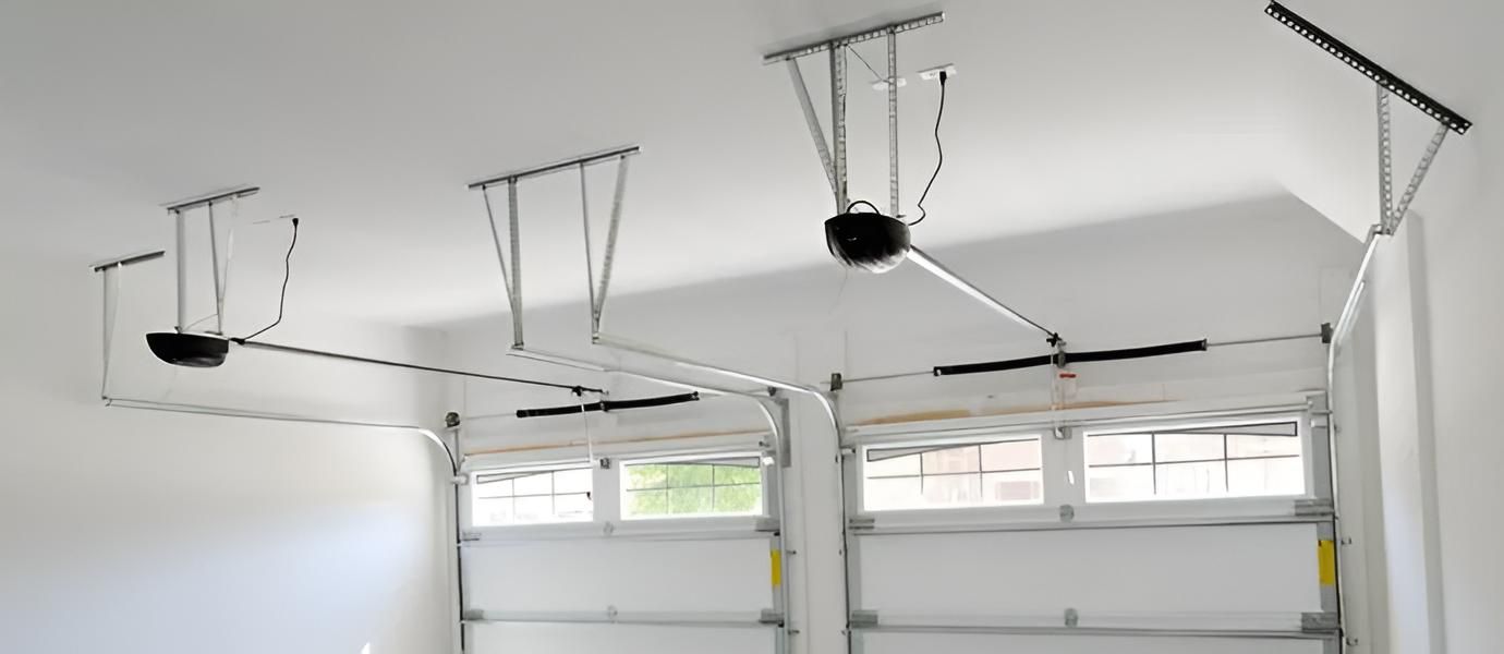 Garage ceiling with several hanging pulley-mounted exercise or storage fixtures above two garage doors