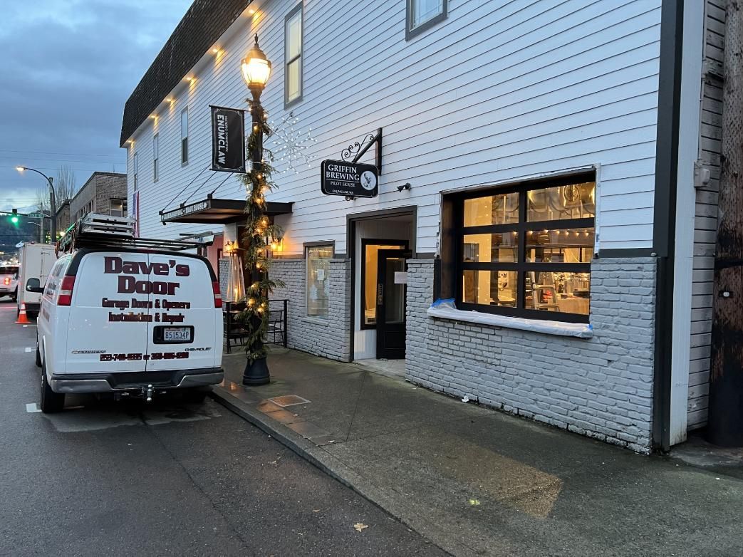 White building exterior with a parked delivery van and lit windows at dusk.