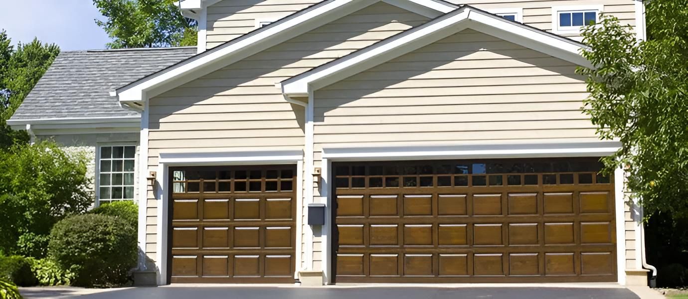 Suburban house with beige siding and two wooden garage doors, front view.