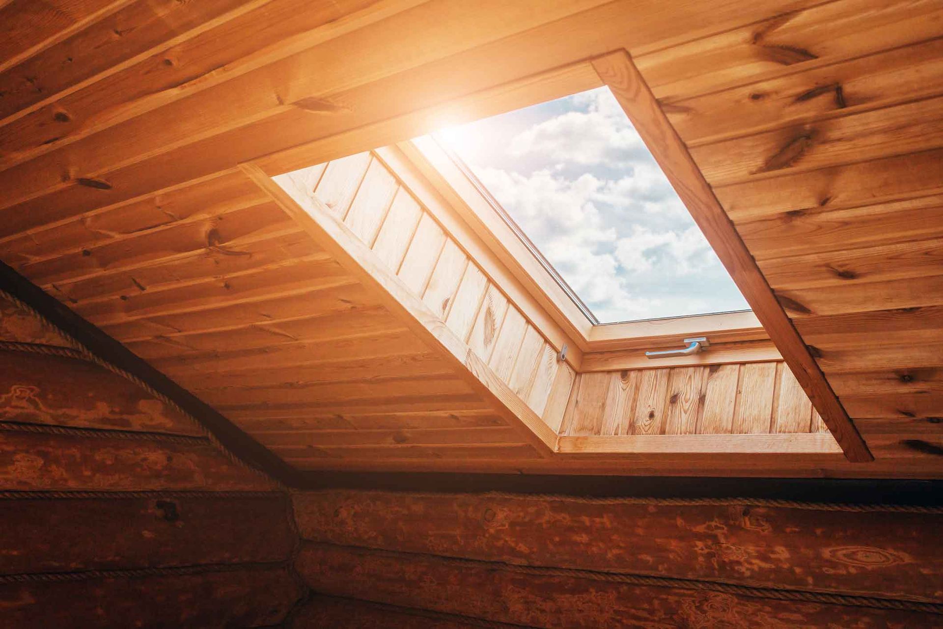 A wooden attic with a skylight in the ceiling.