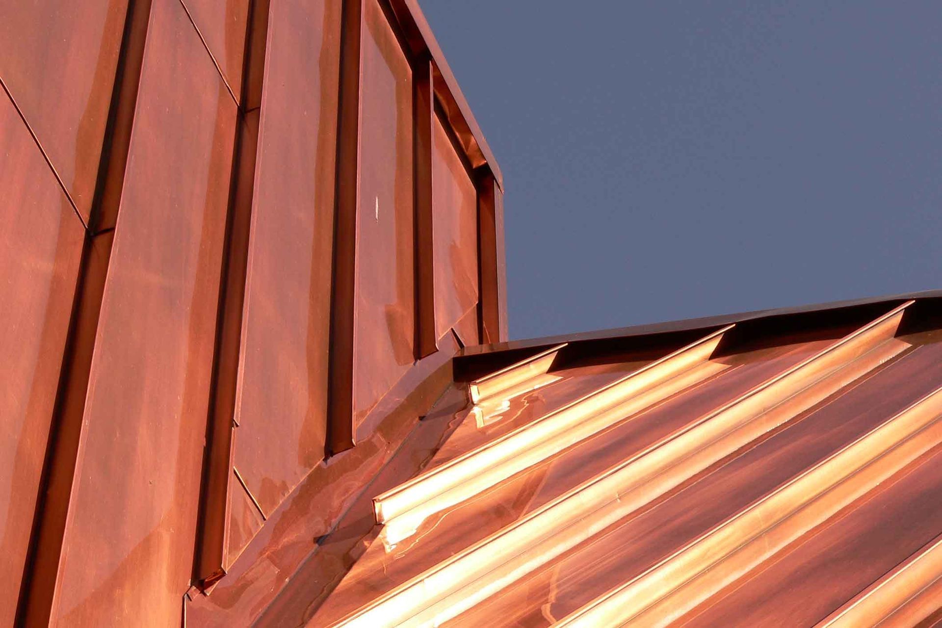 A close up of a copper roof with a blue sky in the background