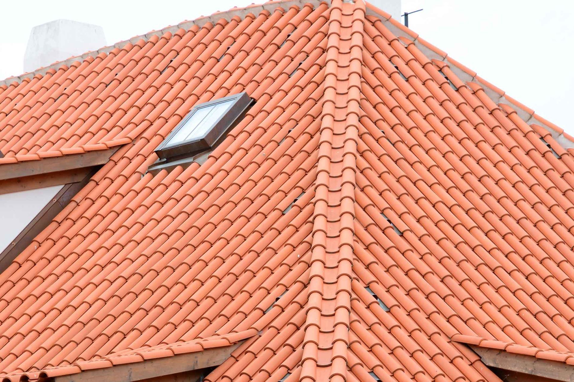 A red tiled roof with a skylight on top of it.