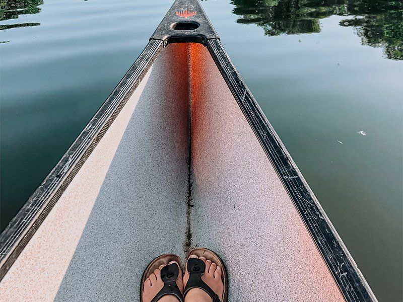A person 's feet are visible in the front of a canoe.