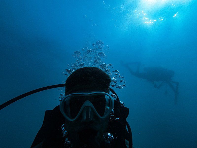 A scuba diver is taking a selfie in the ocean.