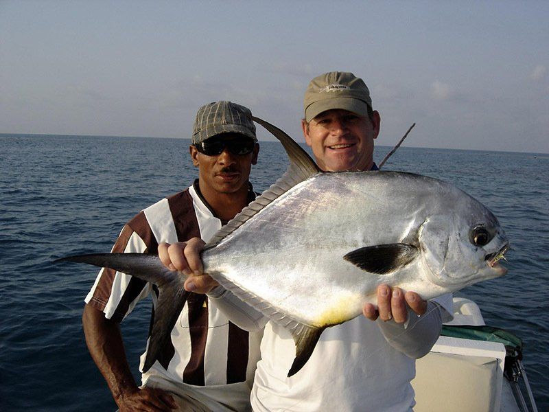 Two men on a boat holding a large fish