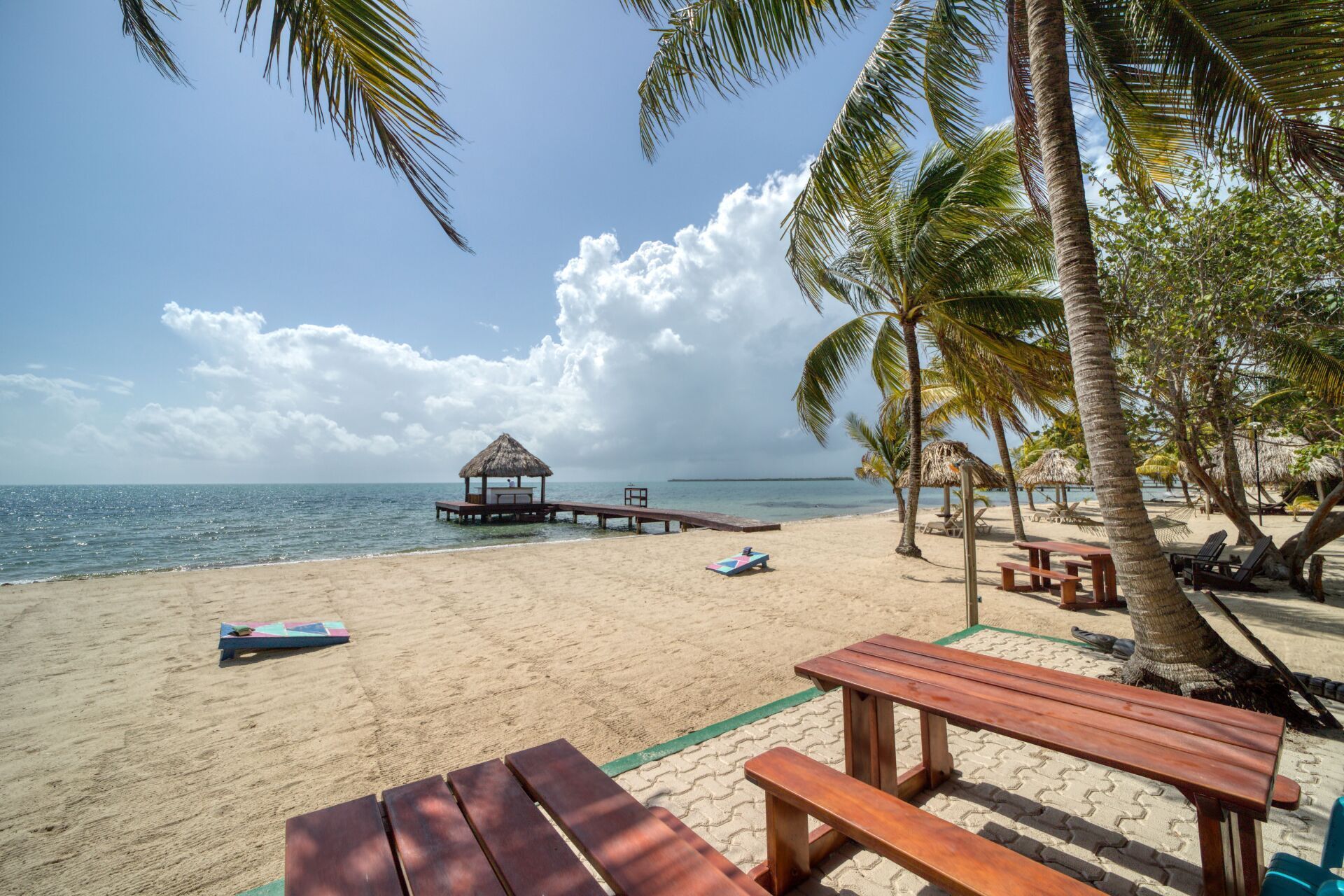 A wooden picnic table is sitting on a sandy beach next to the ocean.