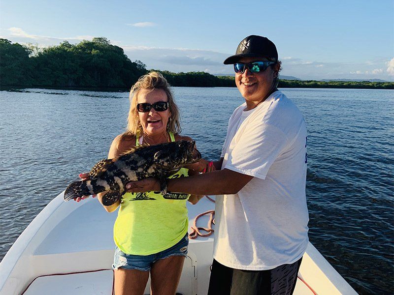 A man and a woman on a boat holding a fish