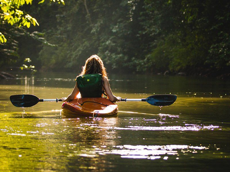 A woman is paddling a kayak on a river.