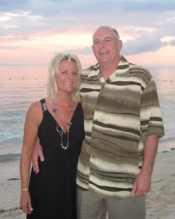 A man and a woman are posing for a picture on the beach