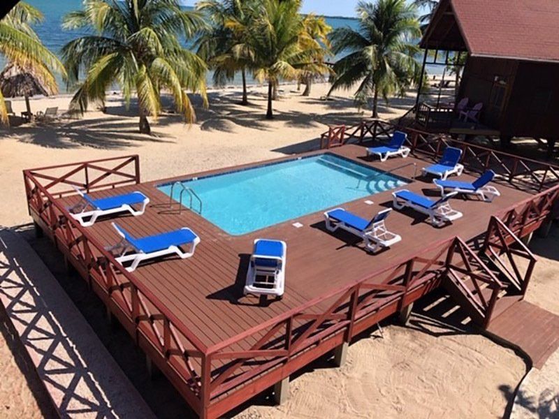 A large swimming pool surrounded by chairs and a wooden deck
