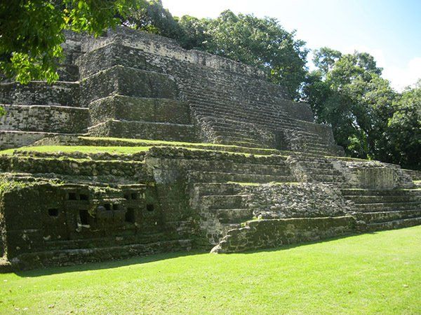 A large stone pyramid is sitting in the middle of a grassy field.