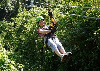 A woman is flying through the air on a zip line.