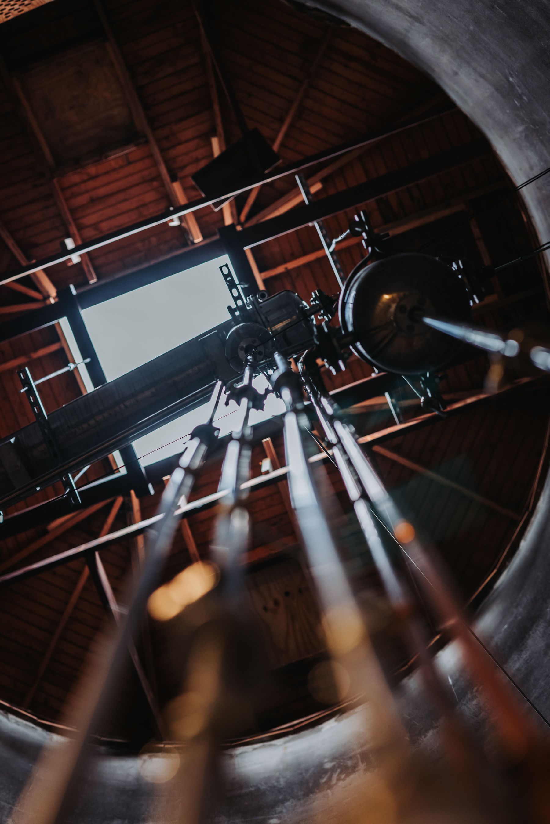 Looking up inside a domed observatory at a large telescope and support system.