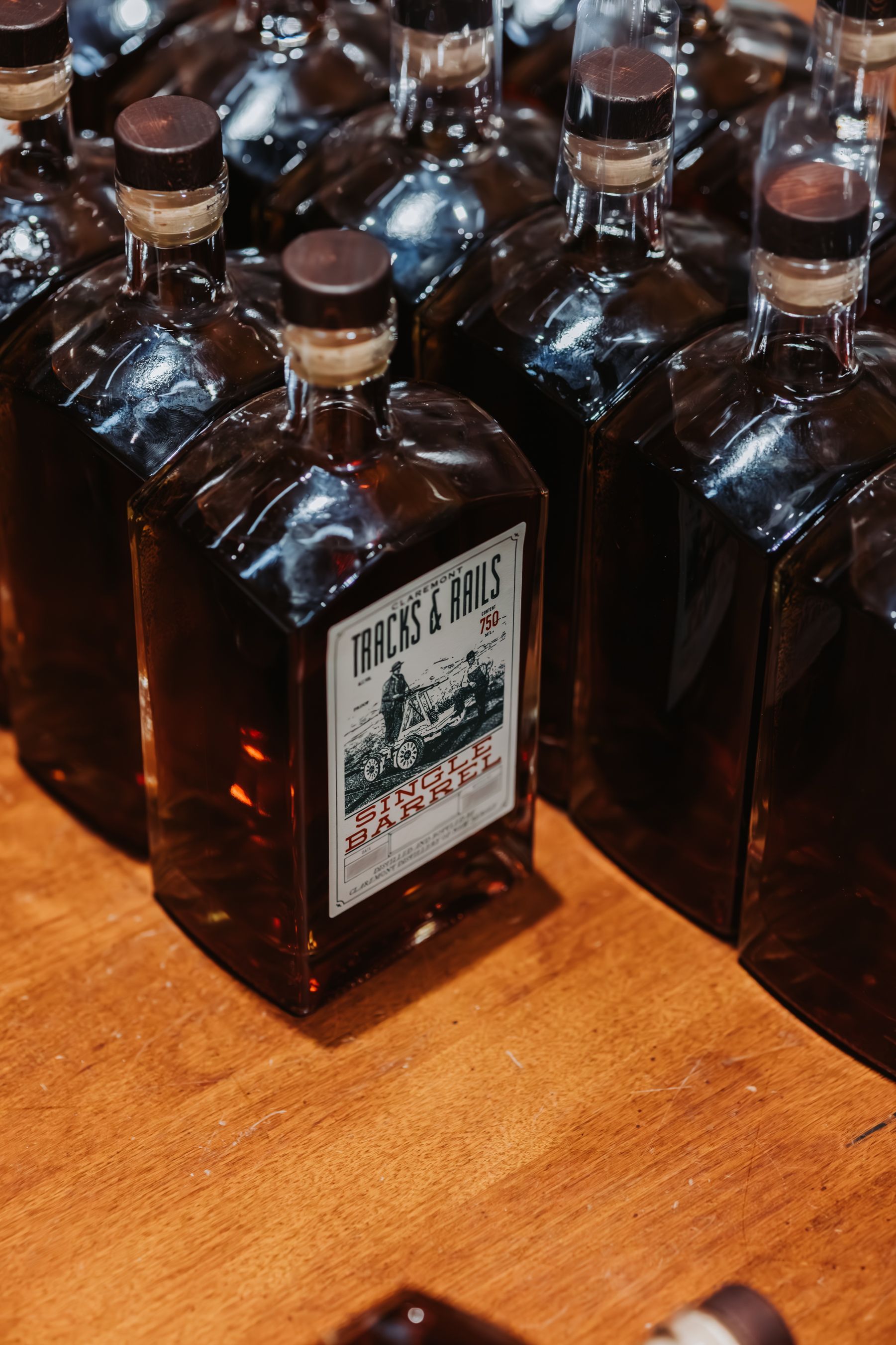 Bottles of liquor with labels, arranged on a wooden surface.