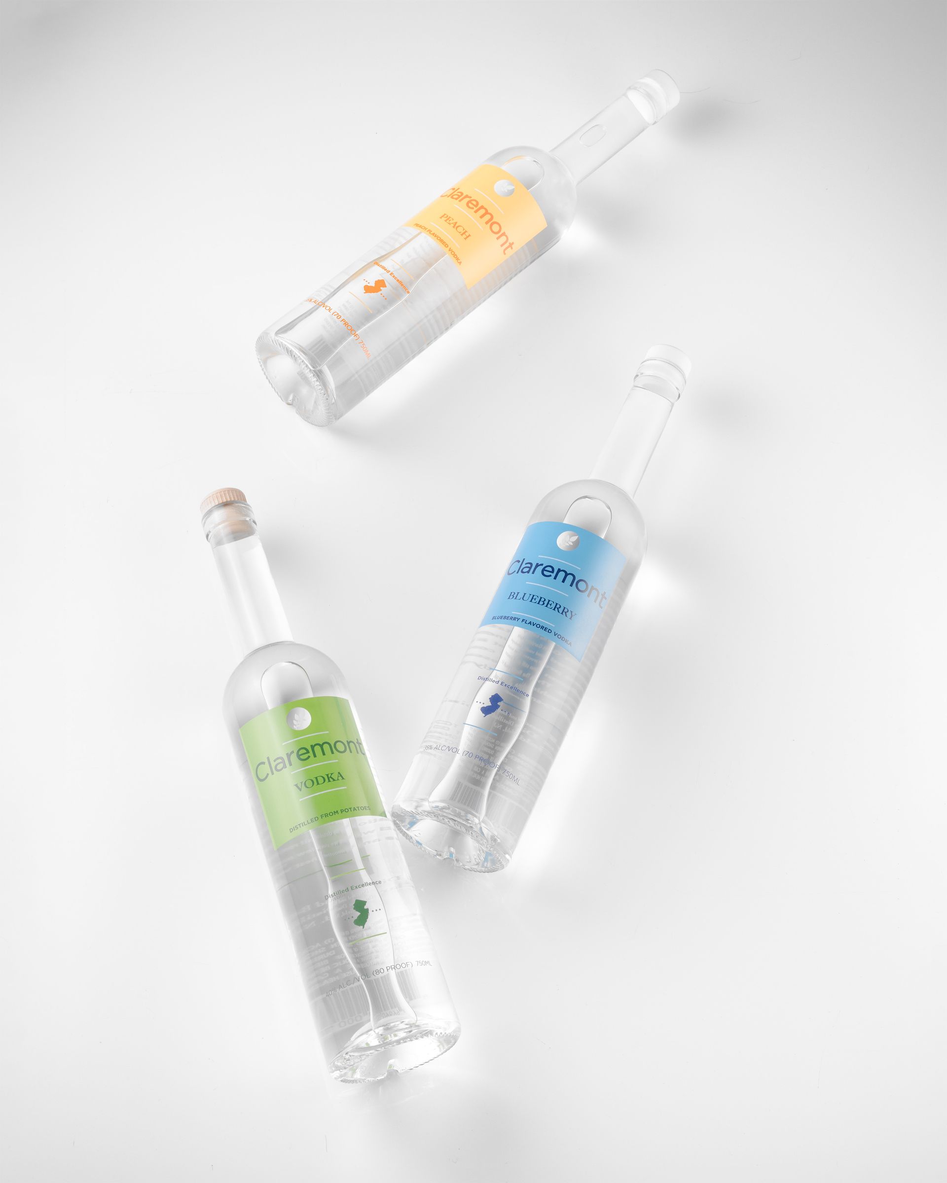 Three clear glass bottles with colorful labels on a white surface.