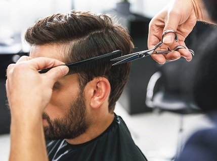 A man getting a haircut using a scissor over comb technique
