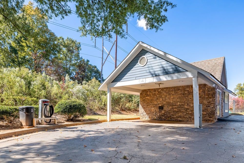 a small stone building with a blue roof is surrounded by trees at Marquis on Edwards Mill in Raleigh, NC.