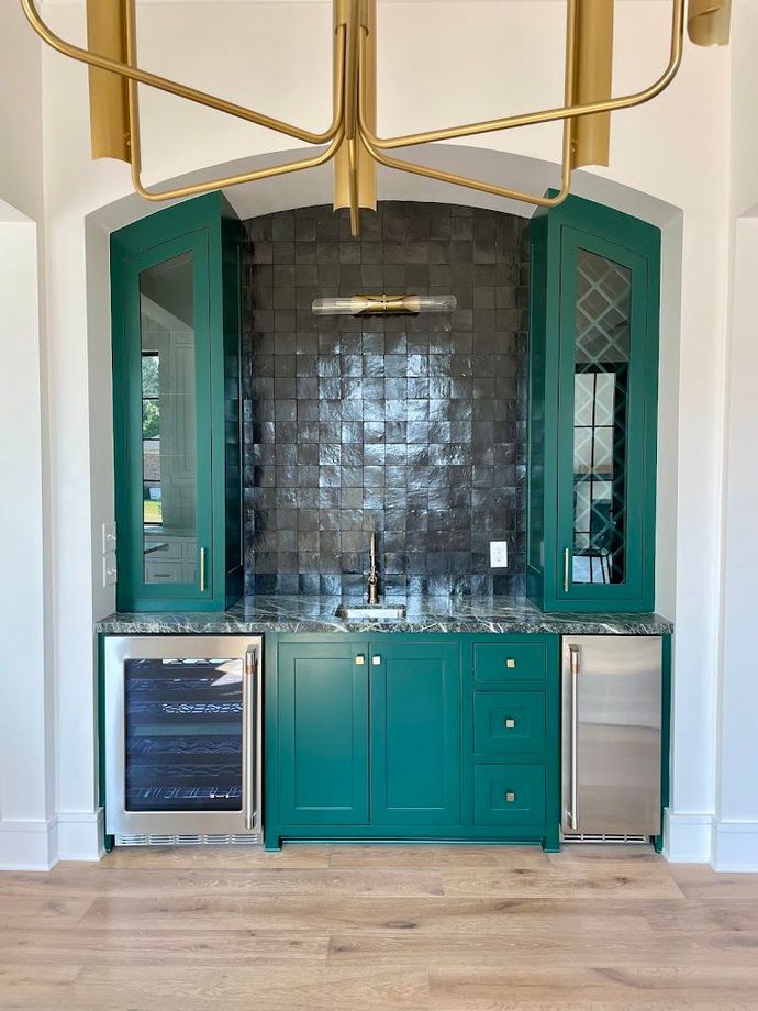Teal bar nook with black tile backsplash, brass light fixture, and built-in cabinets