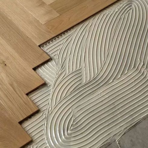 Wood parquet flooring being laid over adhesive on a subfloor in a herringbone pattern