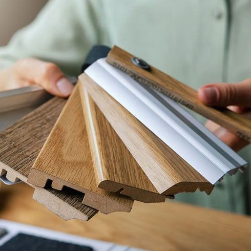 Hands holding a wooden flooring color sample fan with textured finish swatches