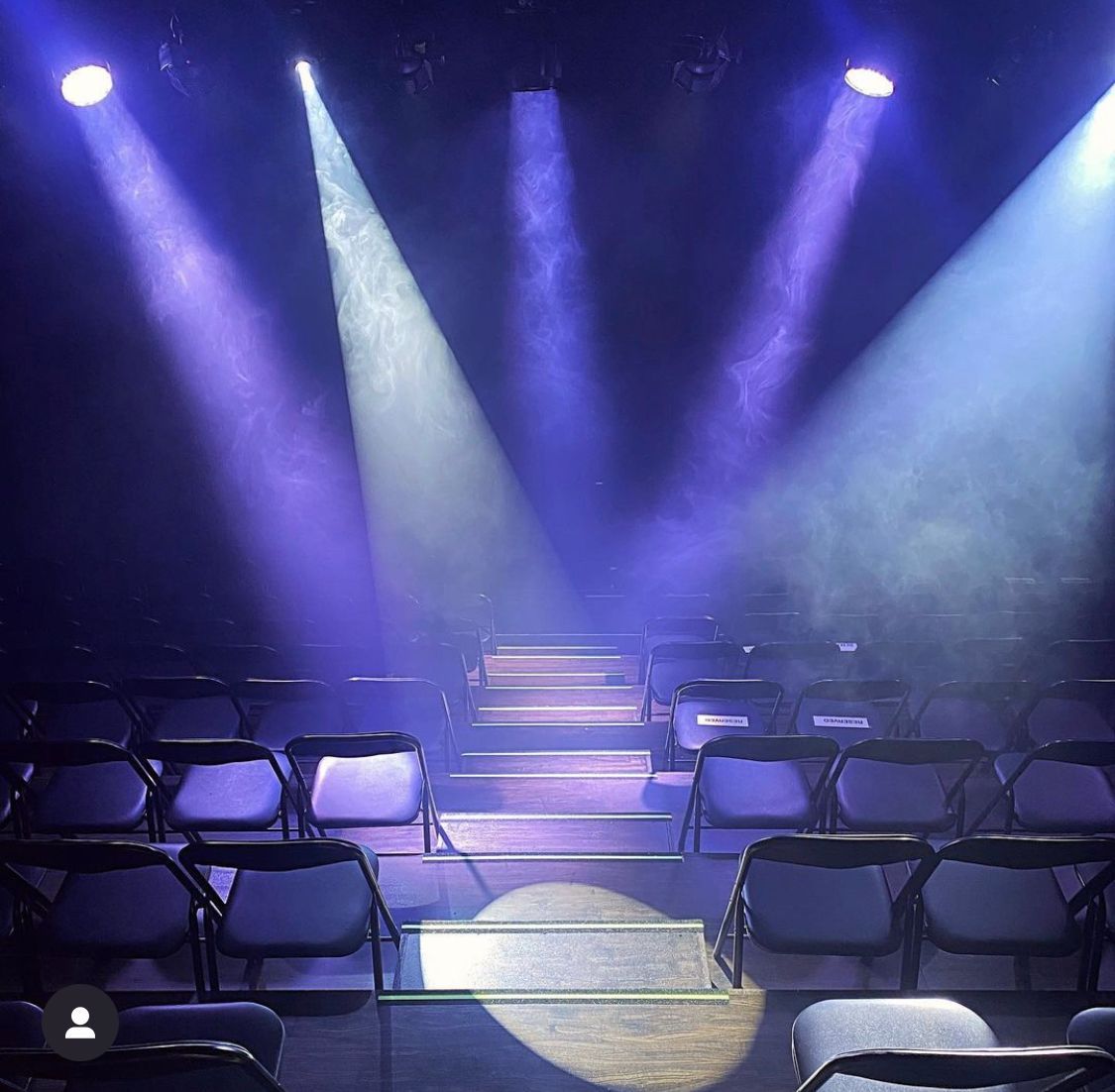  A dimly lit theater with rows of empty black chairs
