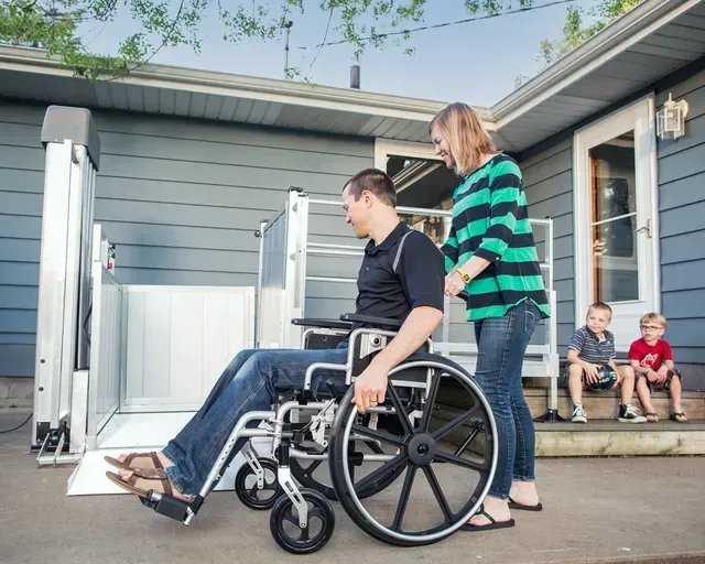 A man in a wheelchair is being pushed by a woman
