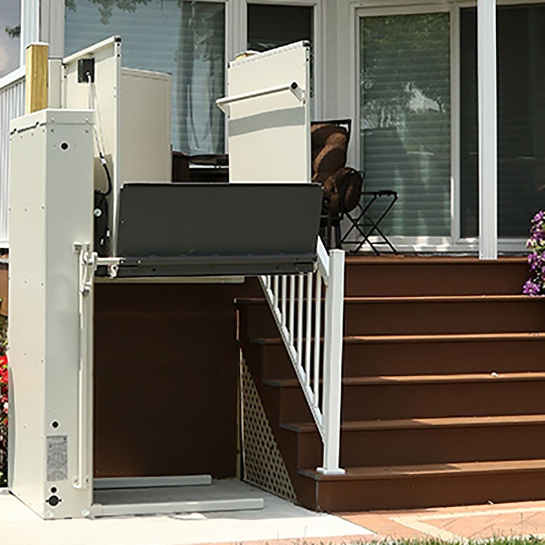A stair lift is sitting on the side of a house next to a set of stairs.
