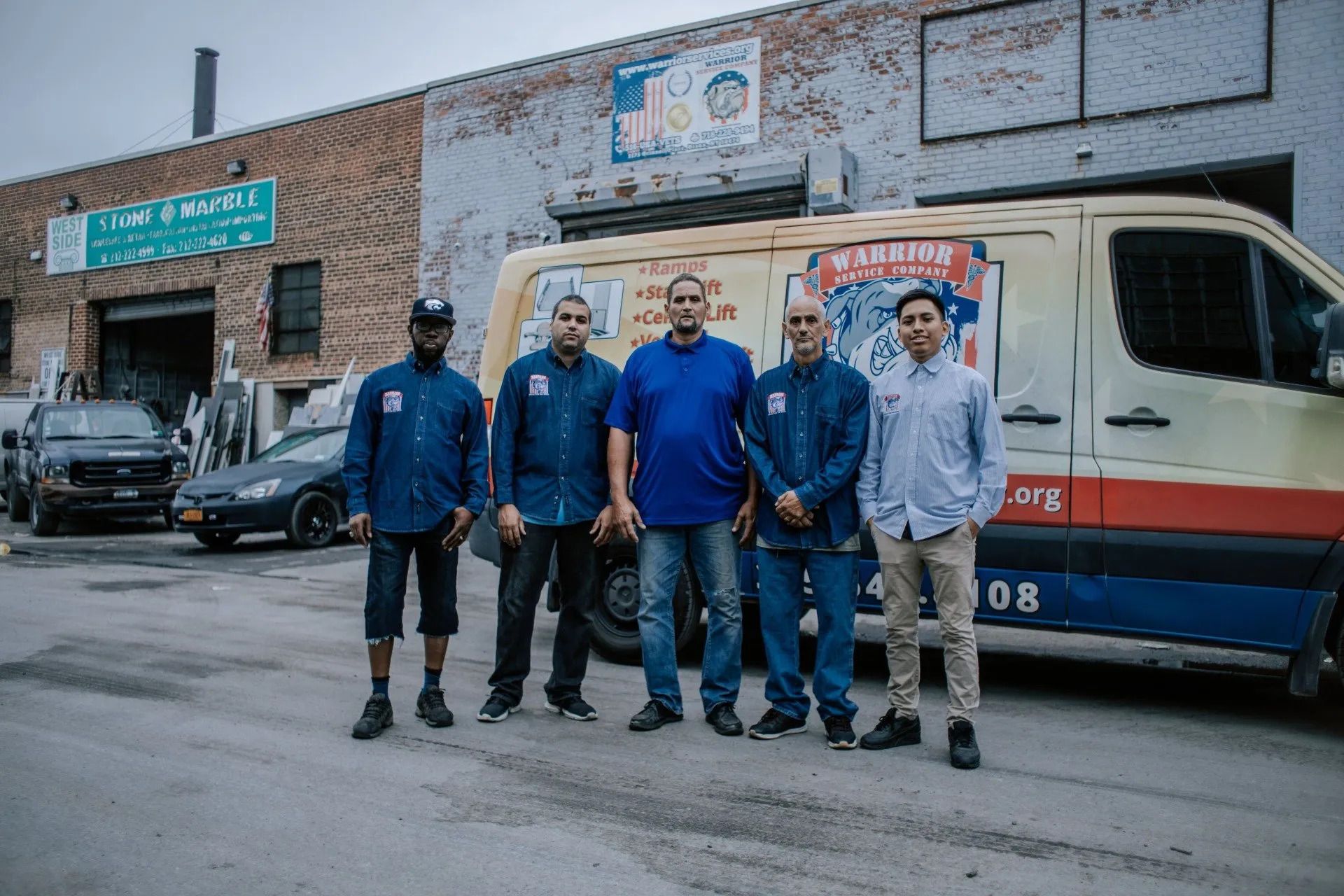 A group of men are posing for a picture in front of a van.
