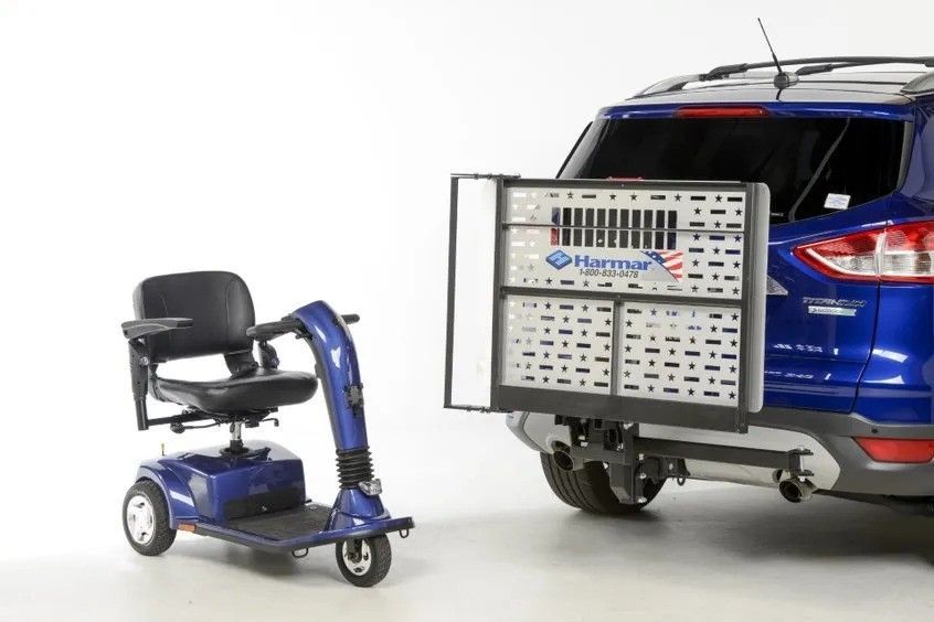 A blue mobility scooter is attached to the back of a blue suv.