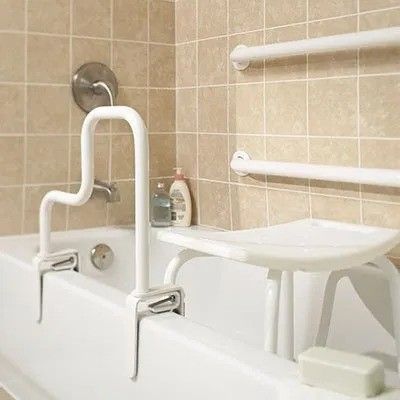 A bathtub with a seat and a railing in a bathroom.