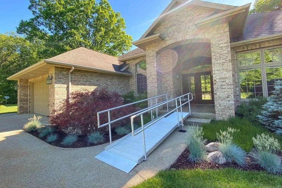 A wheelchair ramp is in front of a brick house.