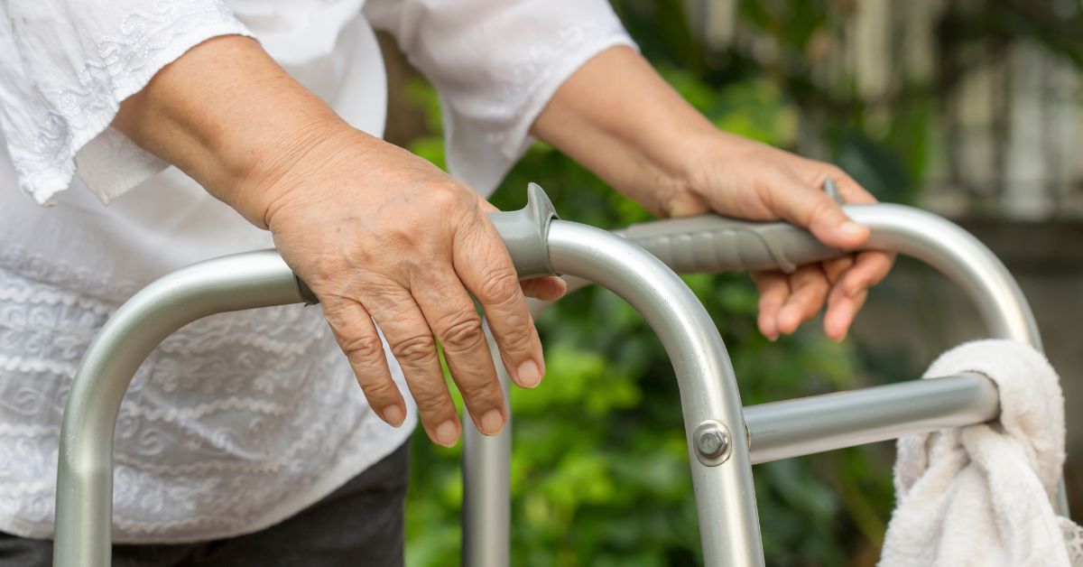Healthcare professional assisting an older adult using a walker during mobility support training